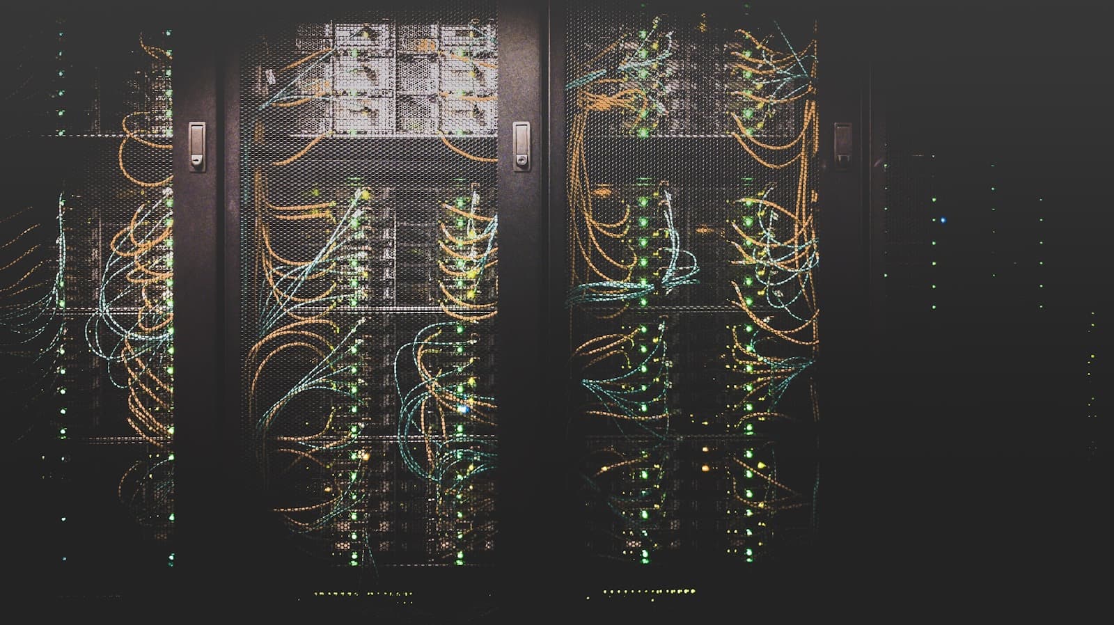 Rows of network equipment behind mesh cabinet doors with coloured cables and indicator lights